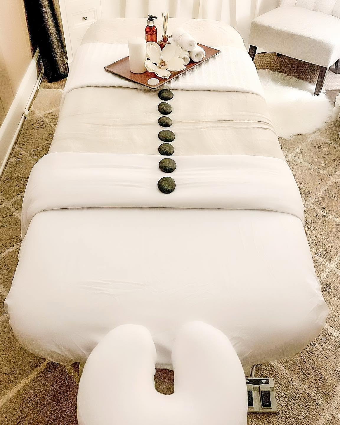 Smooth hot stones laid along the spine of the treatment table, with a linen fold and candle tray